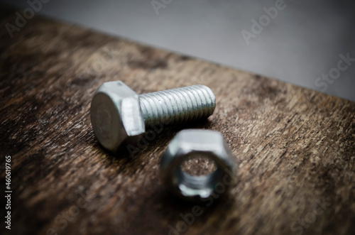 Metal bolt and nut on old wooden background stylized blur background