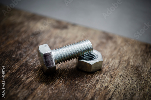 Metal bolt and nut on old wooden background stylized blur background