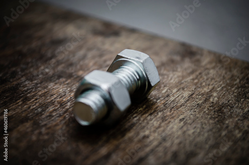 Metal bolt and nut on old wooden background stylized blur background
