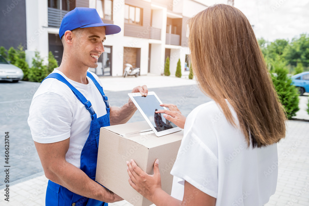 Young courier delivering goods to a young woman at home Young courier delivering goods to a young woman at home