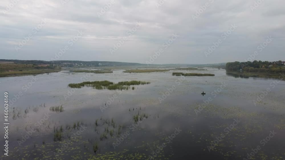 Evening flight over a wild lake and a lone fisherman on a boat. Evening, lake, wild geese, fishing in a boat Evening flight over a wild lake and a lone fisherman on a boat. Evening, lake, wild geese, fishing in a boat