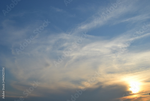 Sun behind clouds on sunset sky.