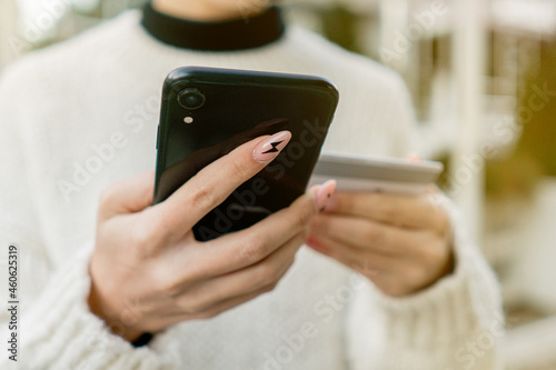 Fototapeta Naklejka Na Ścianę i Meble -  Close-up woman's hands holding a credit card and using smartphone for online shopping