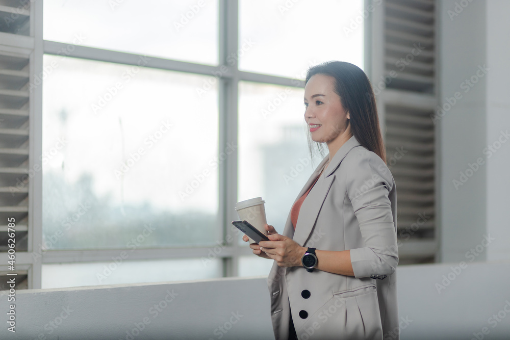 Portrait of an Asian businesswoman in a suit holding coffee and digital tablet in the office. Portrait of an Asian businesswoman in a suit holding coffee and digital tablet in the office.