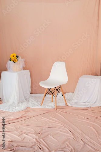 the studio is set up with walls  tables  and the floor is covered with fabric.  setup in the theme of pinkish-orange and white color.