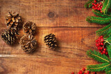 Christmas background. Spruce branches, red berries of potassium and pine cones on a wooden background