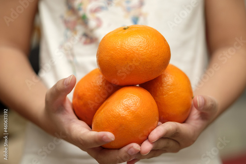 Fresh honey Murcott oranges placed on a man hands, with dressed in white clothes.  photo