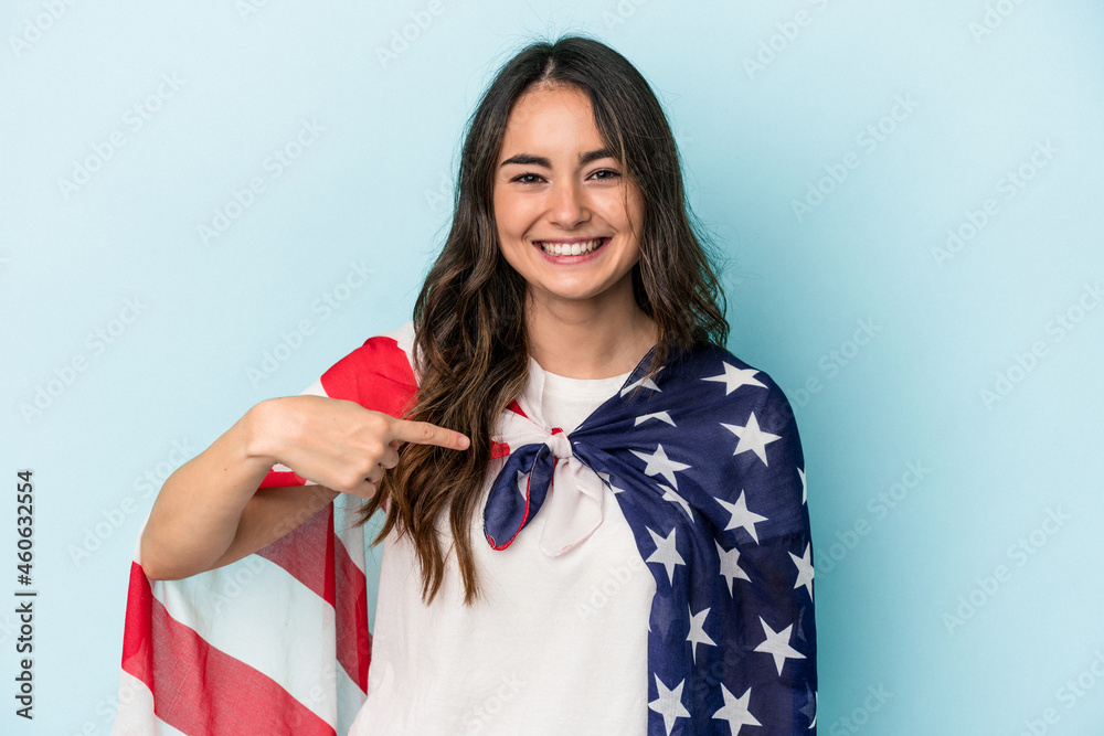 Young caucasian woman holding an American flag isolated on blue background person pointing by hand to a shirt copy space, proud and confident Young caucasian woman holding an American flag isolated on blue background person pointing by hand to a shirt copy space, proud and confident