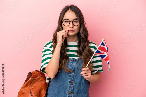 Young caucasian student woman studying English isolated on pink background with fingers on lips keeping a secret.