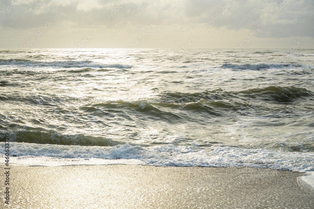 Troubled sea, breaking waves and green water flooded with golden light in the sunset. Troubled sea, breaking waves and green water flooded with golden light in the sunset.