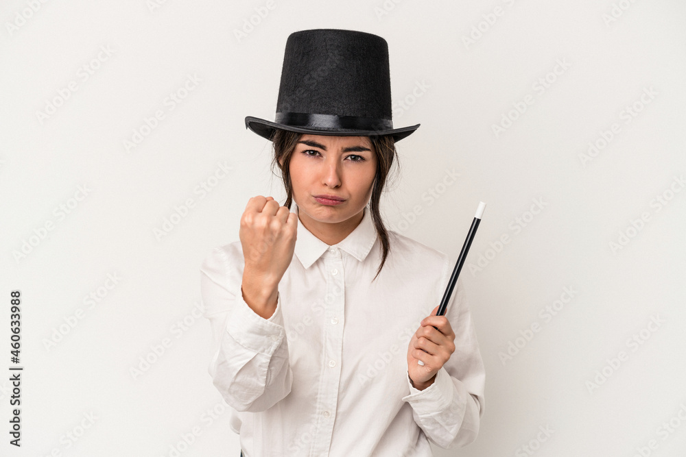 Young magician woman holding a wand isolated on white background showing fist to camera, aggressive facial expression. Young magician woman holding a wand isolated on white background showing fist to camera, aggressive facial expression.