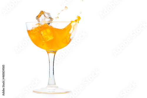Drop ice cubes in to  orange soda in Margarita glass isolated