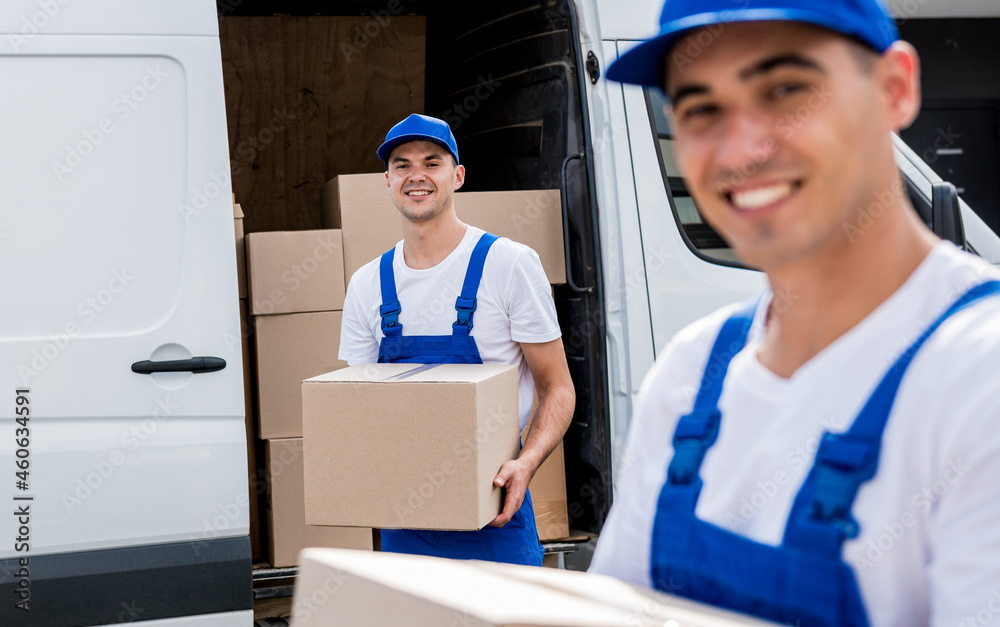 Two removal company workers unloading boxes from minibus into new home Two removal company workers unloading boxes from minibus into new home