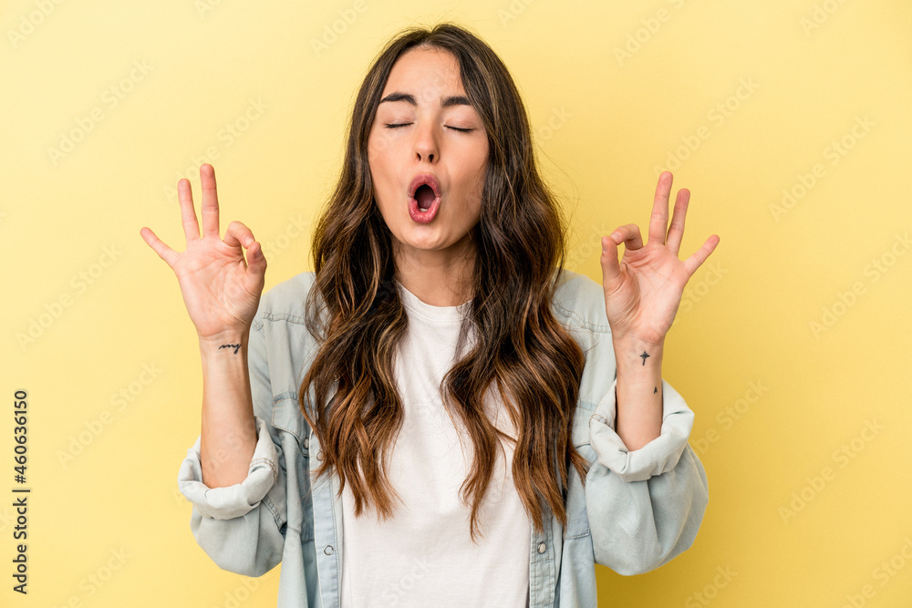 Young caucasian woman isolated on yellow background relaxes after hard working day, she is performing yoga. Young caucasian woman isolated on yellow background relaxes after hard working day, she is performing yoga.