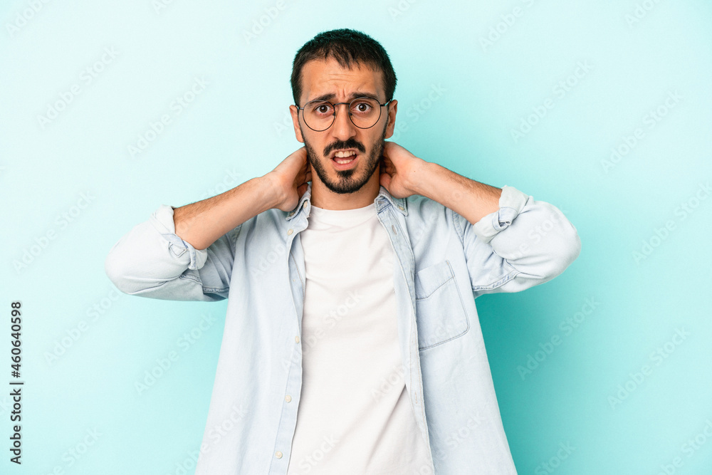 Young caucasian man isolated on blue background touching back of head, thinking and making a choice. Young caucasian man isolated on blue background touching back of head, thinking and making a choice.