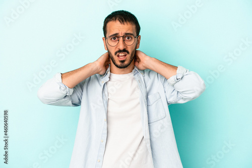 Young caucasian man isolated on blue background touching back of head, thinking and making a choice. © Asier