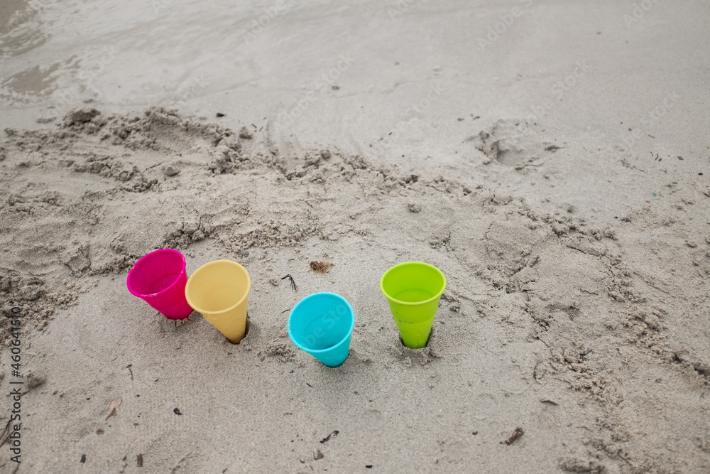 Colorful plastic cones toys on the sand of a beach shore Colorful plastic cones toys on the sand of a beach shore
