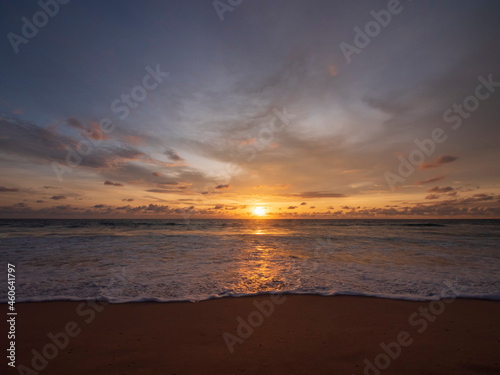 Beautiful sunset over the calm sea with cloud sky background. Sunset over tropical beach. Nature summer  concept. Peak sunset over sea with yellow light reflect on sea water. Tranquil seascape.