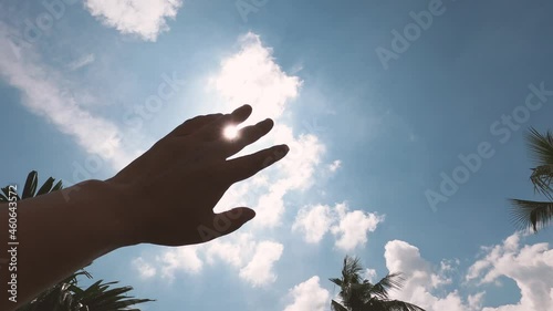 Hot summer sunlight rays pouring through human hand. Hand covering sun light heat temperature. Protection from ultraviolet light and sunburn background. Sunstroke, heatstroke, greenhouse effect.