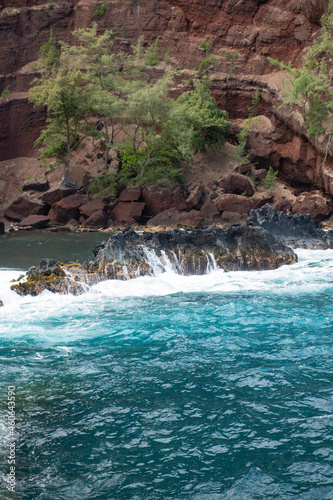 Ocean waves crashing on the rocky island coast. Splashing ocean waves and stones. Red Sand Beach  Maui in in Hawaiian.