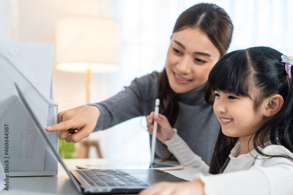 Asian little young girl kid learning online class at home with mother. Asian little young girl kid learning online class at home with mother.