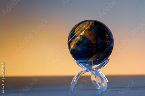 Polished Tiger’s Eye Crystal Sphere Reflecting Golden Light on Clear Display Stand
