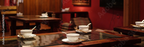 White porcelain tableware and bamboo chopsticks on wooden table in traditional Yunnan cuisine restaurant with red interior wall