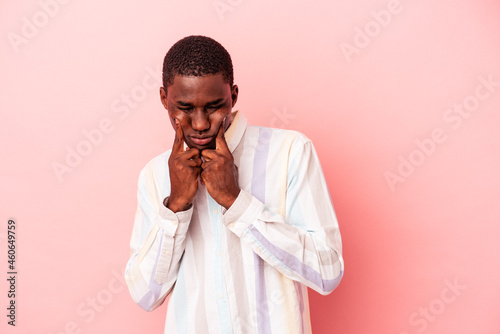 Young African American man isolated on pink background crying, unhappy with something, agony and confusion concept.