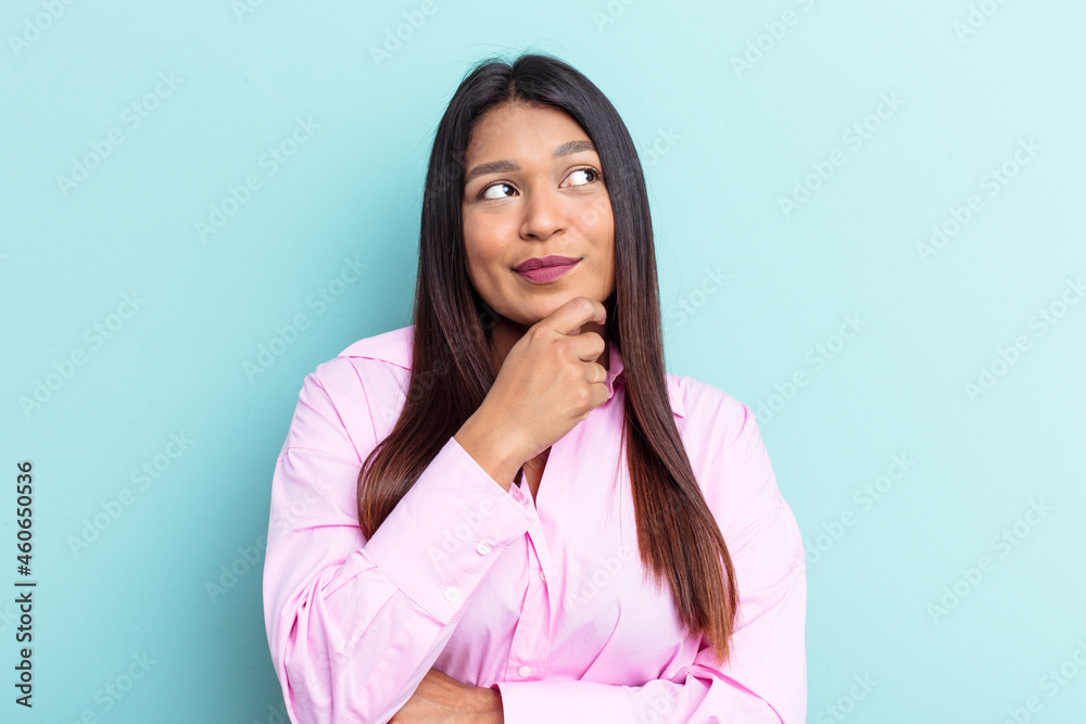 Young Venezuelan woman isolated on blue background looking sideways with doubtful and skeptical expression. Young Venezuelan woman isolated on blue background looking sideways with doubtful and skeptical expression.