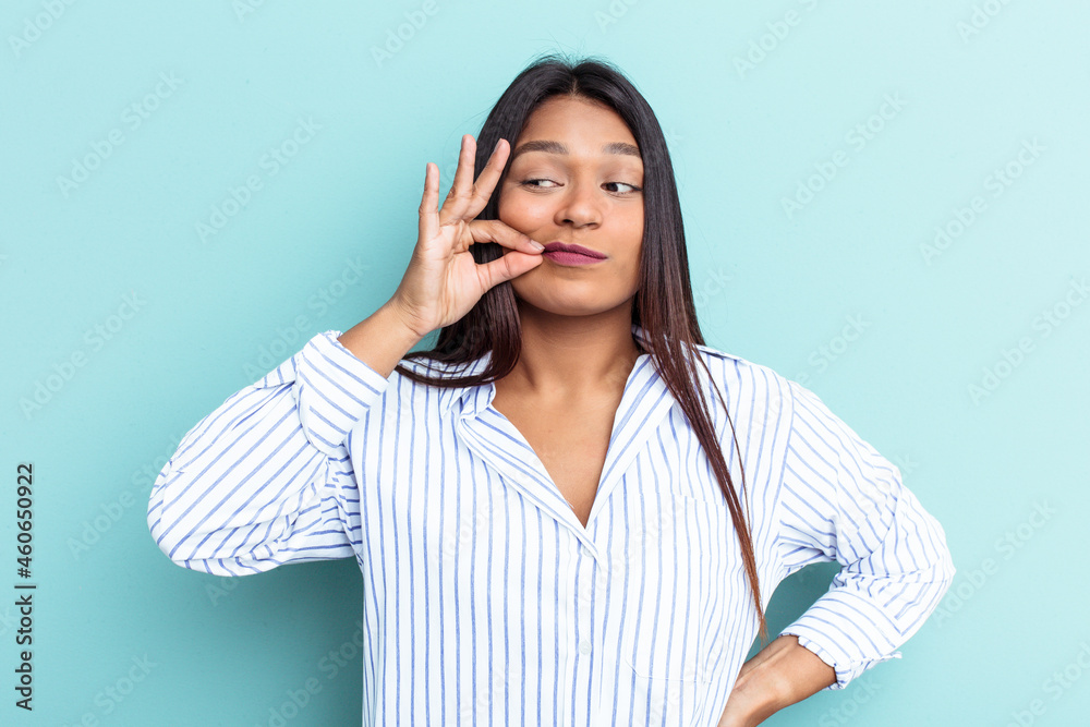 Young Venezuelan woman isolated on blue background with fingers on lips keeping a secret. Young Venezuelan woman isolated on blue background with fingers on lips keeping a secret.