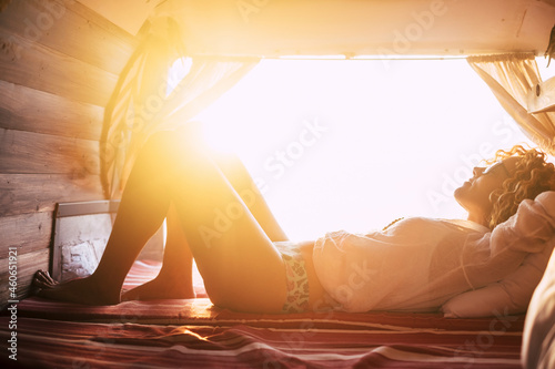 Young woman in eyeglasses sleeping in van. Beautiful woman enjoying vacation on road trip. Silhouette of woman in underwear relaxing in car during holiday road trip