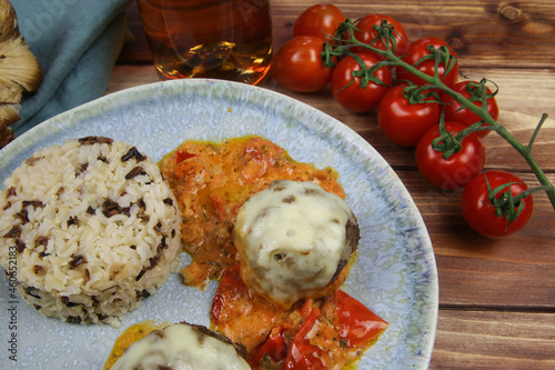 Closeup of blue plate on wood table with homemade minced meat balls gratinated with mozzarella cheese in fresh tomato sauce with rice photo