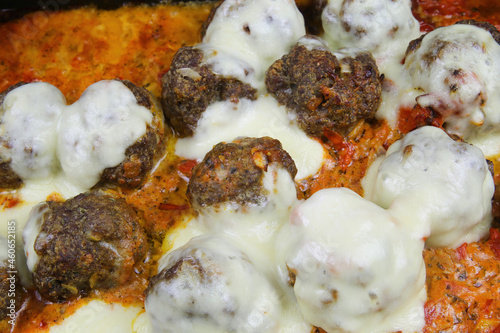 Closeup of isolated oven casserole with minced meat balls gratinated with mozzarella cheese in fresh tomato sauce photo