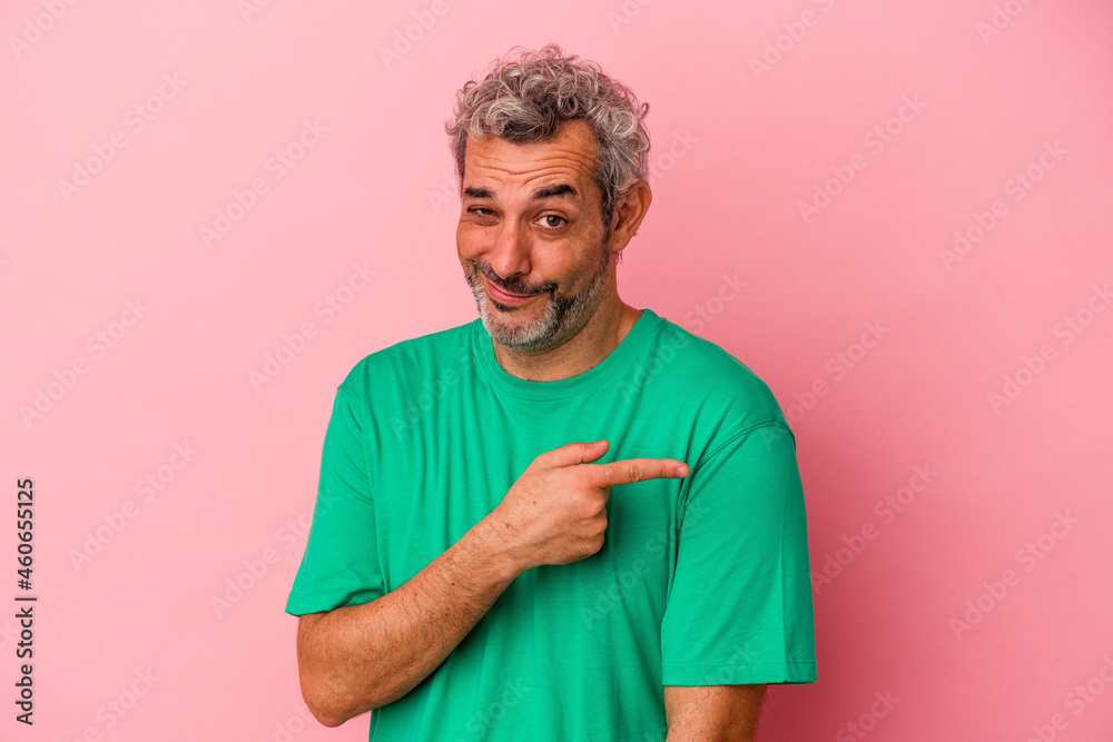 Middle age caucasian man isolated on pink background smiling and pointing aside, showing something at blank space. Middle age caucasian man isolated on pink background smiling and pointing aside, showing something at blank space.
