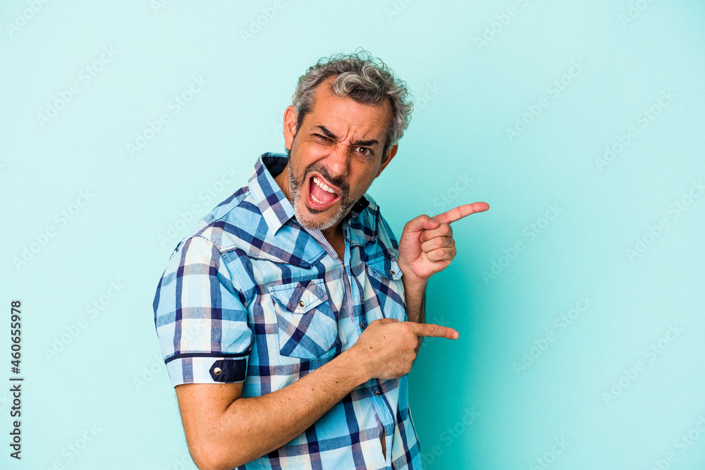 Middle age caucasian man isolated on blue background pointing with forefingers to a copy space, expressing excitement and desire. Middle age caucasian man isolated on blue background pointing with forefingers to a copy space, expressing excitement and desire.