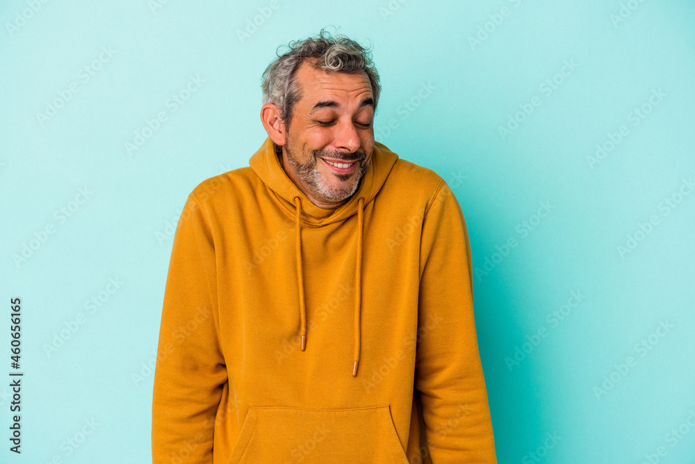 Middle age caucasian man isolated on blue background laughs and closes eyes, feels relaxed and happy. Middle age caucasian man isolated on blue background laughs and closes eyes, feels relaxed and happy.
