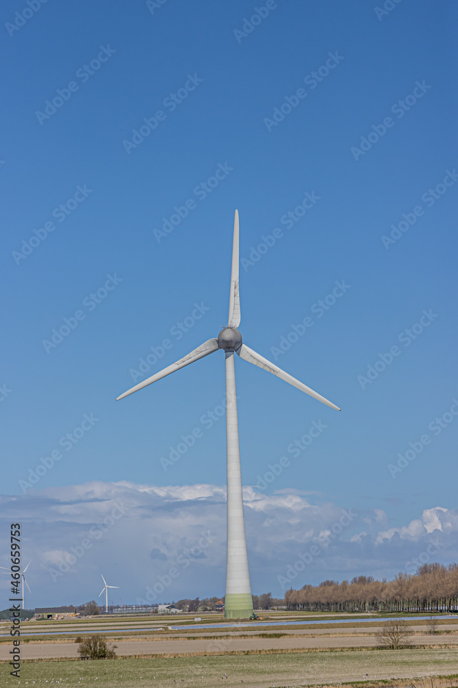 Huge windmill between farmland with other mills, farms and trees in the background, sunny day with a blue sky with white clouds, sunny day Noord-Holland in the Netherlands Huge windmill between farmland with other mills, farms and trees in the background, sunny day with a blue sky with white clouds, sunny day Noord-Holland in the Netherlands