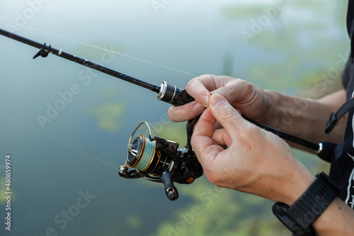 Close up view of fisherman putting silicone bait on the hook of fishing rod