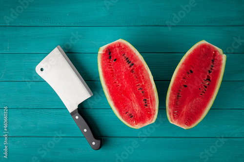 Watermelon sliced in a half with a backsword on the wooden turquoise background. Red juicy summer fruit berry photo