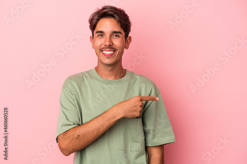 Young mixed race man isolated on white background smiling and pointing aside, showing something at blank space.