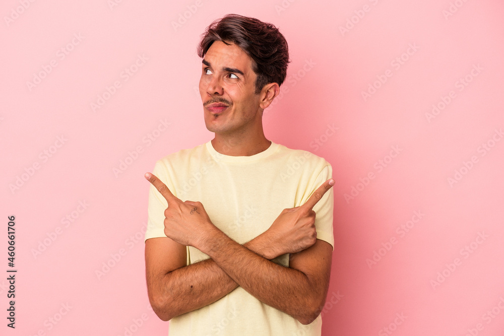 Obraz premium Young mixed race man isolated on white background points sideways, is trying to choose between two options.