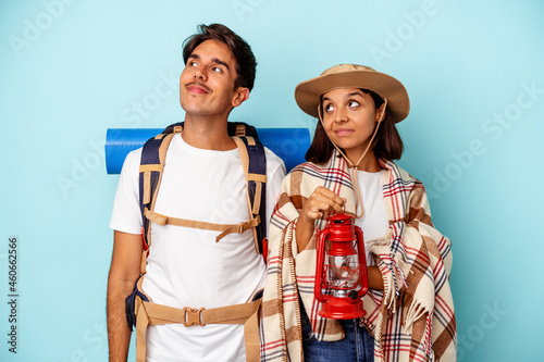 Young mixed race hiker couple isolated on blue background dreaming of achieving goals and purposes
