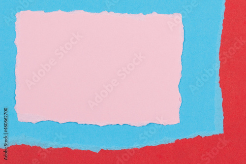 Torn paper textured collage background. Grunge ripped pastel pink paper piecs with ragged edge on geometric blue and red paper background