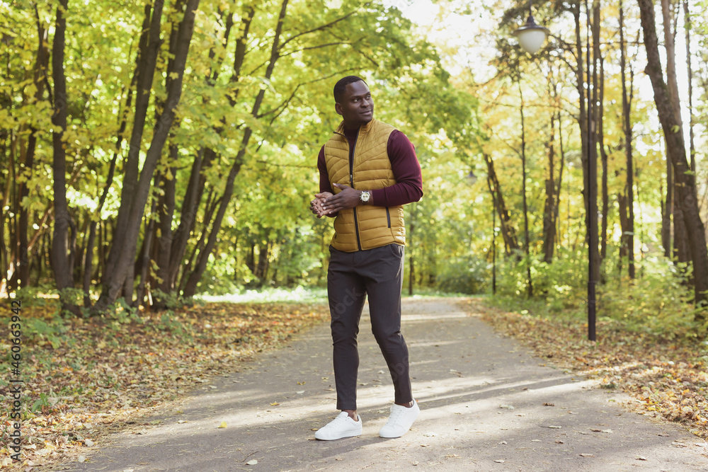 African american student walking in the park in autumn season