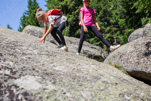 Little girls climbing on rocks formation in forest
