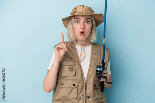 Young caucasian fisherwoman holding a rod isolated on blue background having some great idea, concept of creativity.