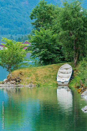 Fototapeta White boat at shore with green lake.