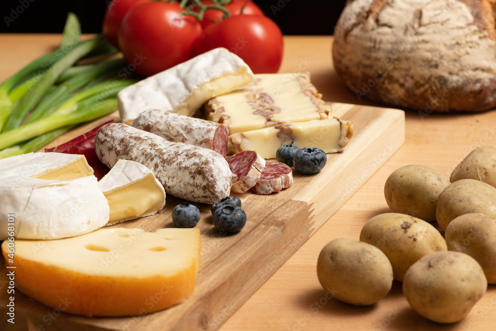 Tisch mit Holz und Käse Holzplatte, mit frischem Brot, Tomaten und Kartoffeln. Traditionelle Brotzeit für gesunde Ernährung. Tisch mit Holz und Käse Holzplatte, mit frischem Brot, Tomaten und Kartoffeln. Traditionelle Brotzeit für gesunde Ernährung.