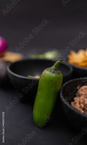 Chili pepper leaning against bowls of tortilla chips and refried beans