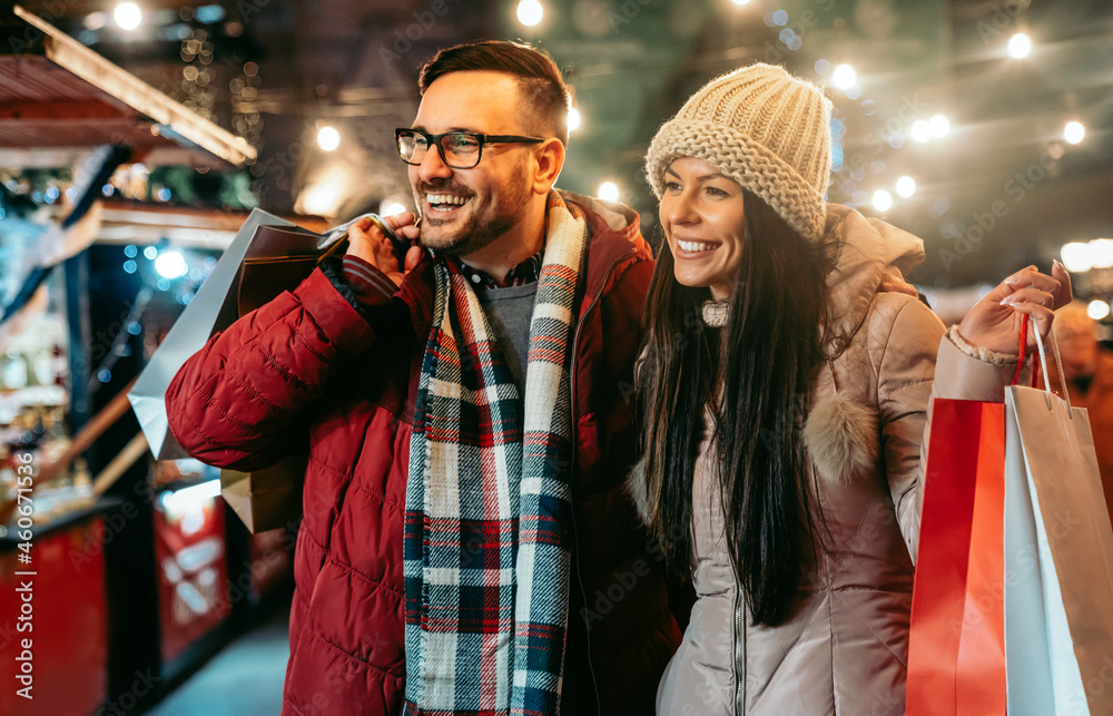 Romantic Christmas shopping. Happy young couple buying gifts for family. Sale and people concept.